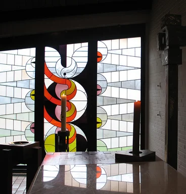 Glasfenster im Hintergrund | Altartisch und brennende rote Kerze im Vordergrund