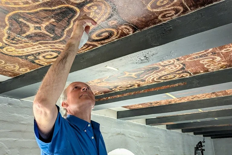 Ein Mann zeigt Deckenmalereien
