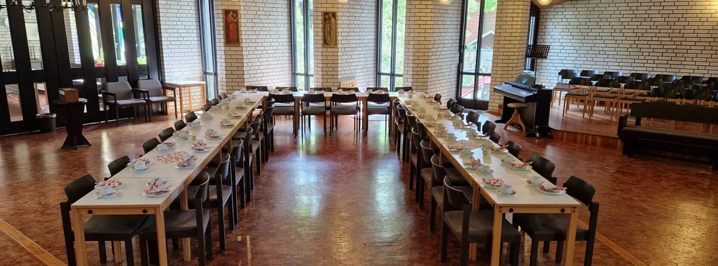 Tische und Stühle in U-Form für ein Frühstück gedeckt in einem Kirchenraum