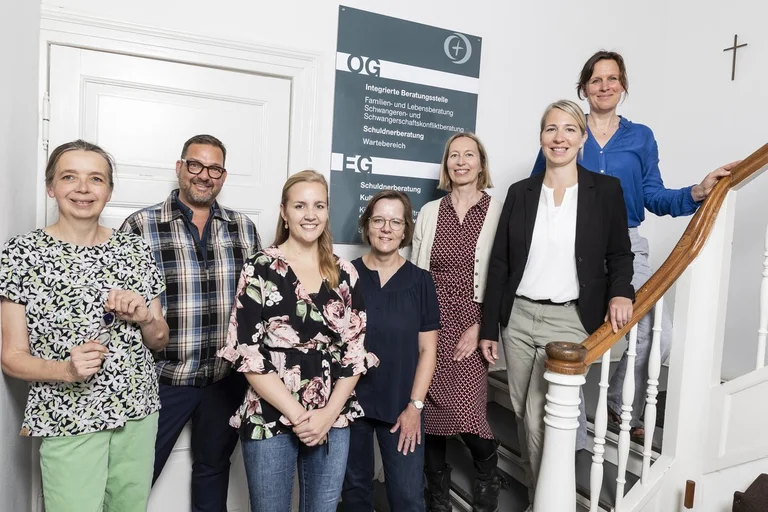 Mehrere Menschen stehen in einem Treppenhaus