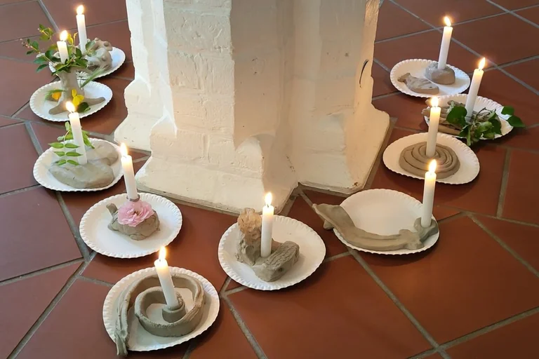 Kerzen auf Tellern stehen um eine Säule