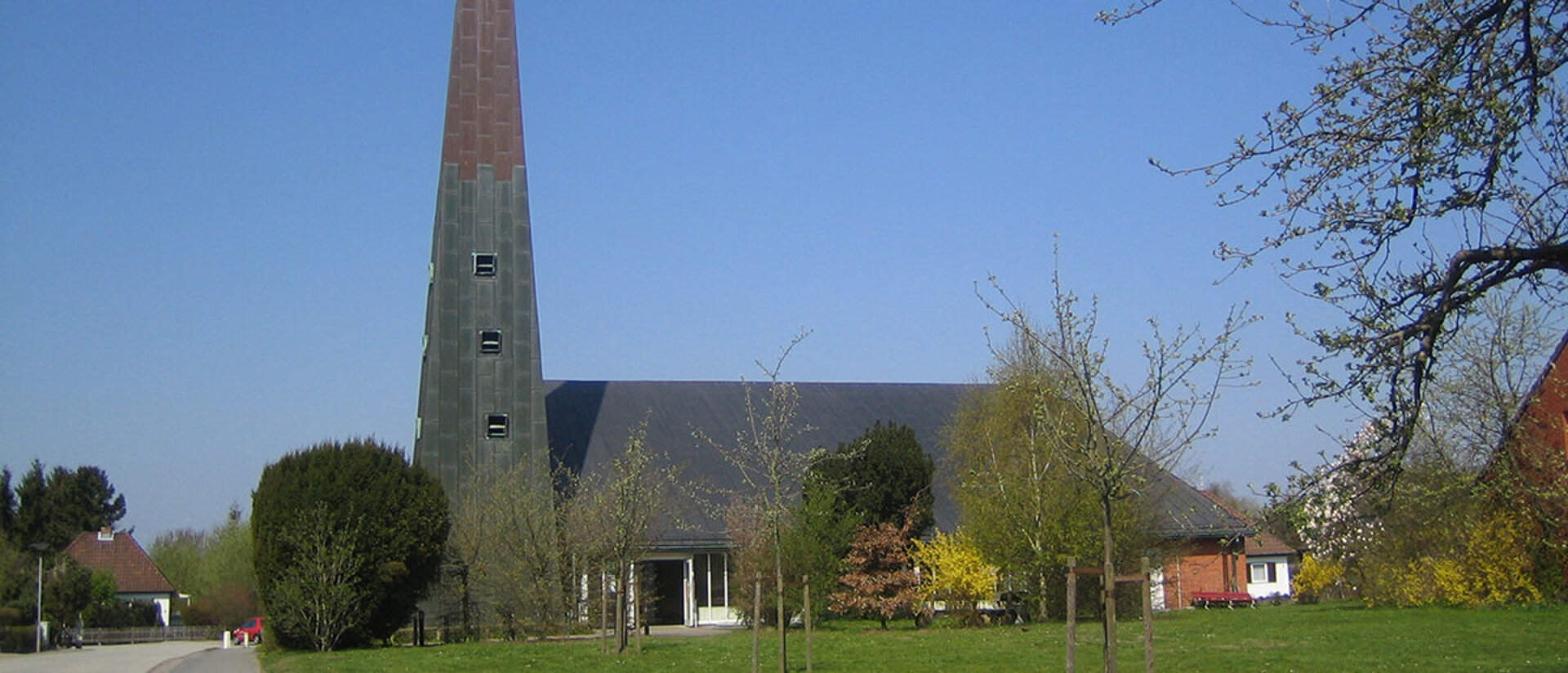 Außenansicht der Paul-Gerhardt-Kirche mit umliegenden Bäumen und Wiese