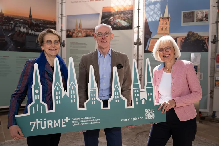 Drei menschen in einer Kirche halten ein Schild in den Händen. 